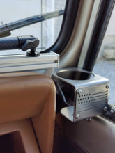 Load image into Gallery viewer, A photo of a dashboard accessory mount holding a phone mount in a tan-colored Jeep YJ
